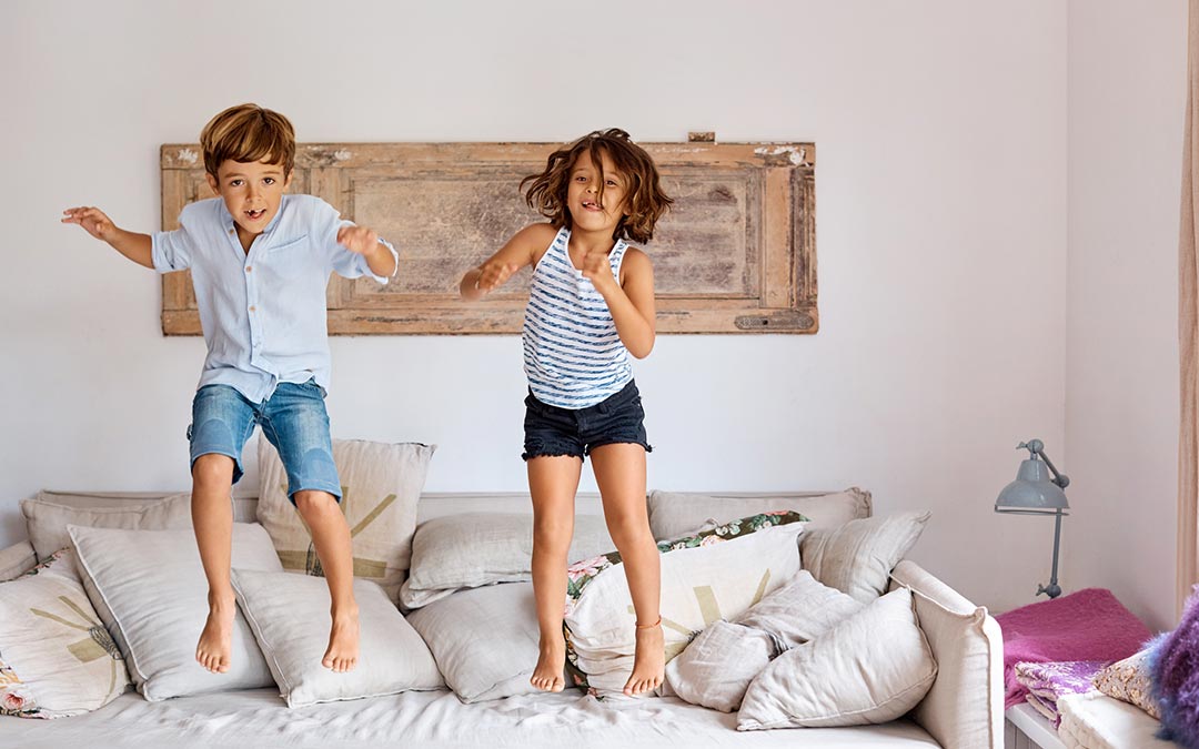 two happy kids jumping on a sofa