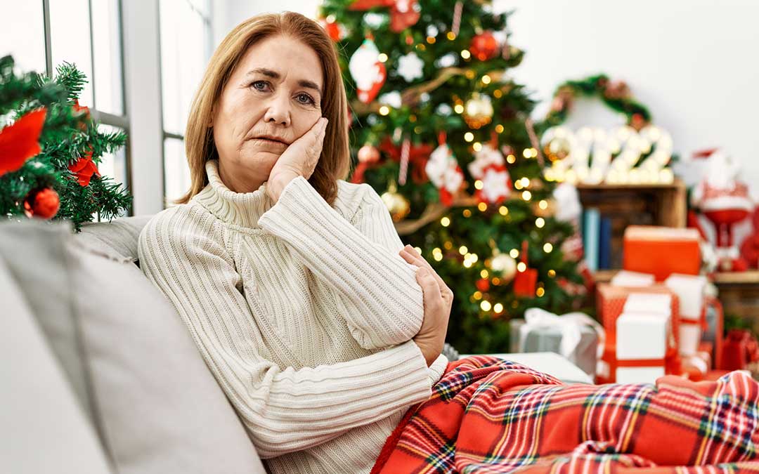 woman sitting on the sofa by christmas tree thinking looking tired and bored