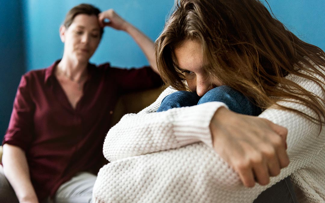 parent, adult child with arms wrapping around herself