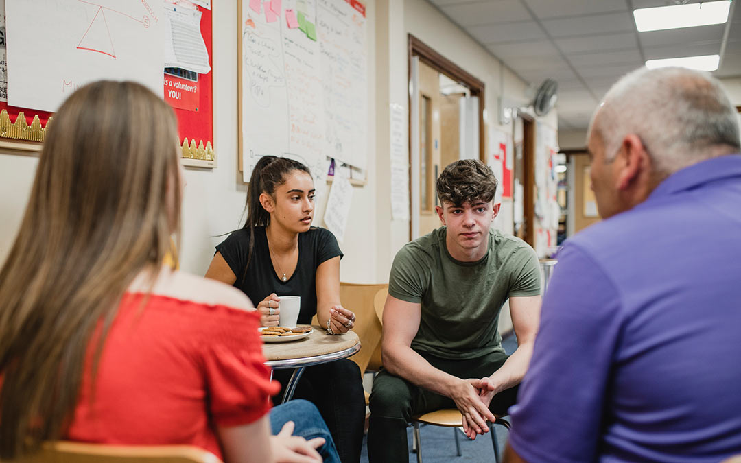 three teenagers speaking with a school social worker