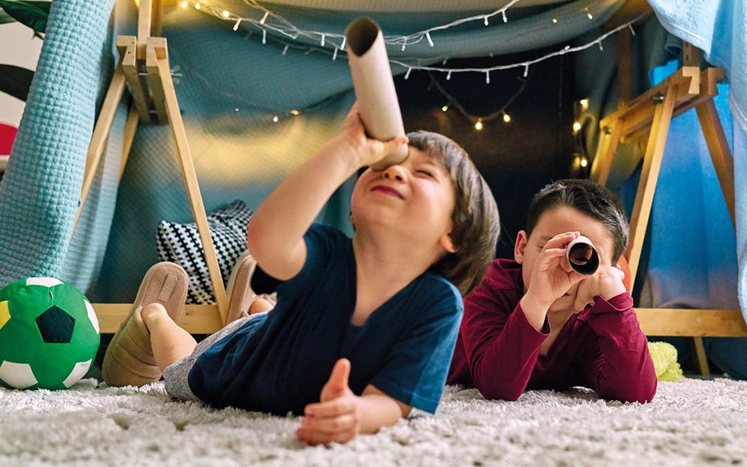 two children playing together in a tent in their house