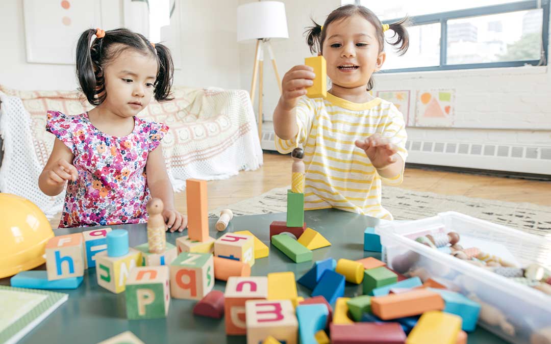two toddlers playing with blocks together