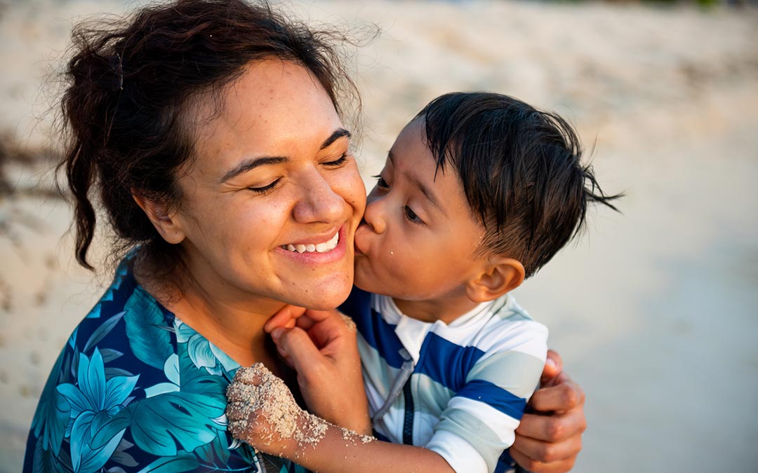 mom and young son enjoying a hug on the beach