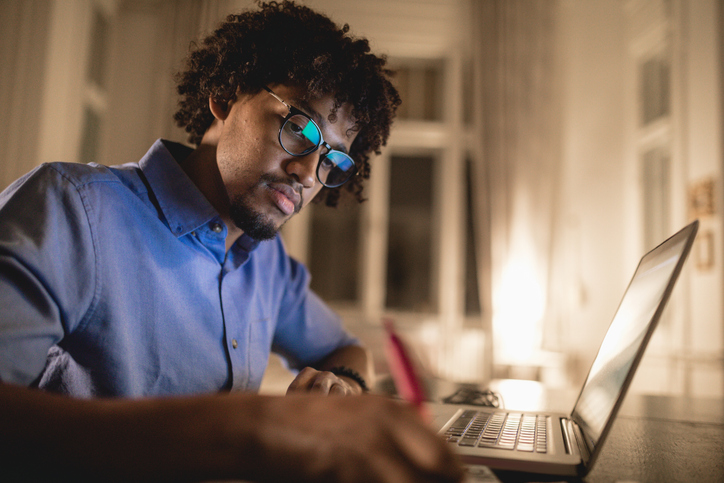 young man studying at nigh, with laptop computer