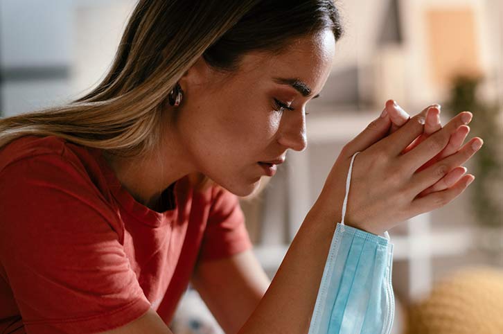 worried young woman holds a face mask