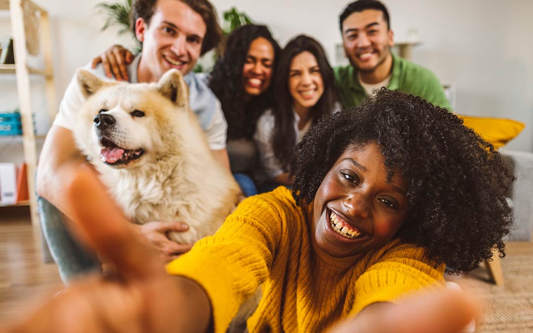 group of friends and family on sofa posing for a selfie with a dog