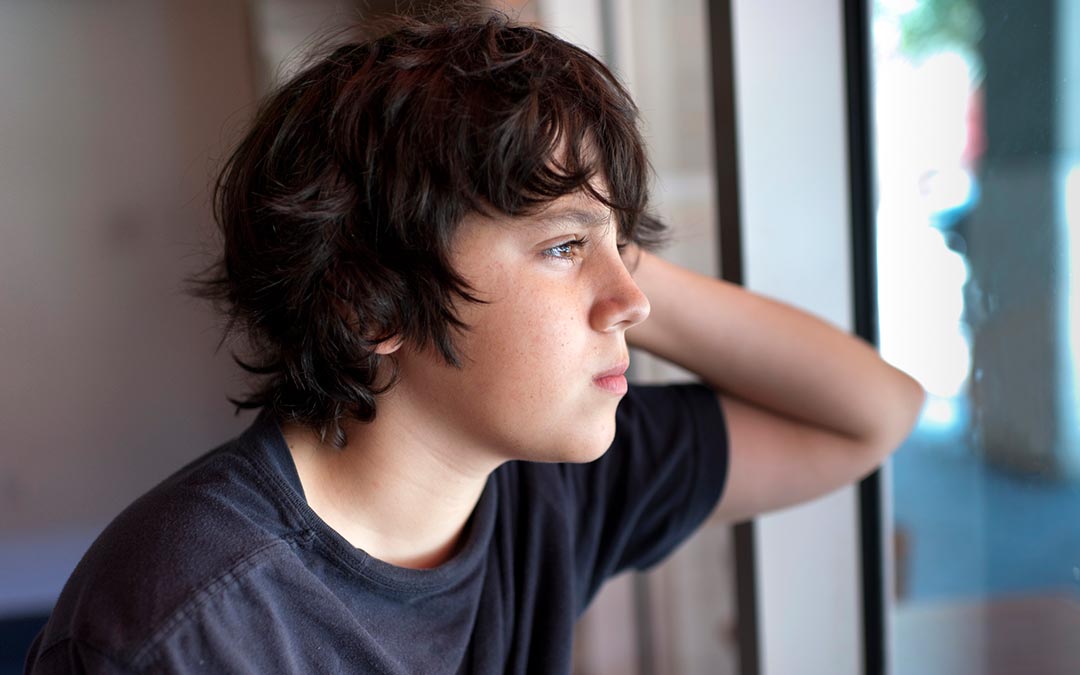 pensive child looking through a window